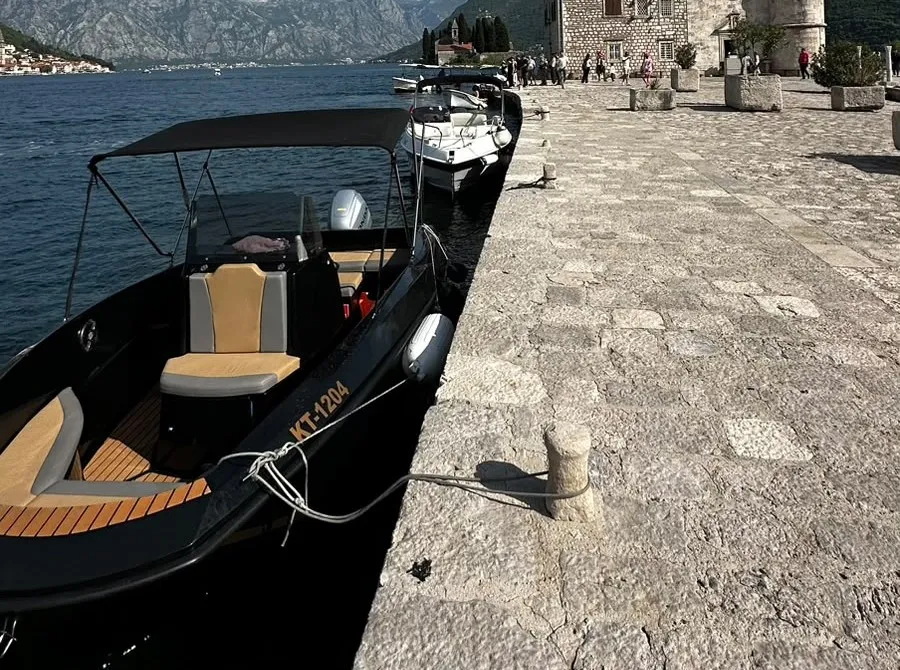 Our small speedboat with its sun canopy, moored at a stone quay